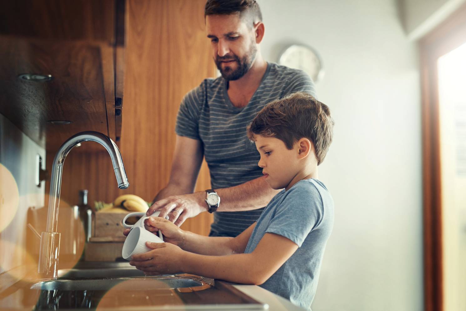 dad and son washing dishes with clean water