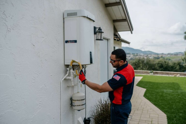 Goettl technician inspecting an outdoor tankless water heater
