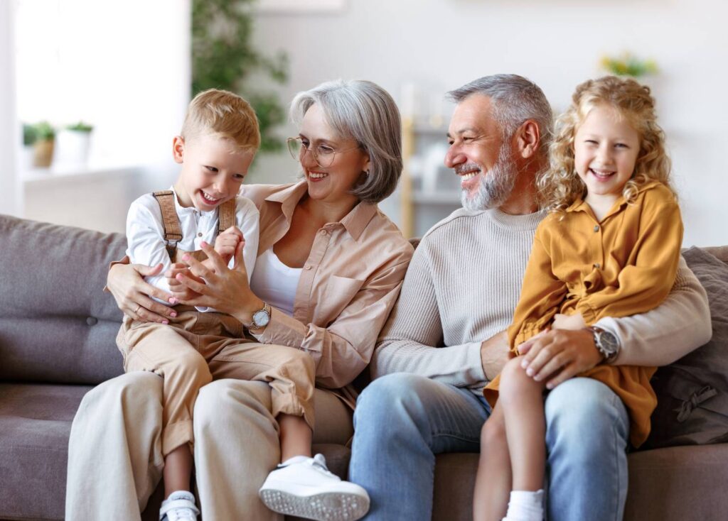 Grandparents with grandchildren cozy on the couch after sewer and drain service.