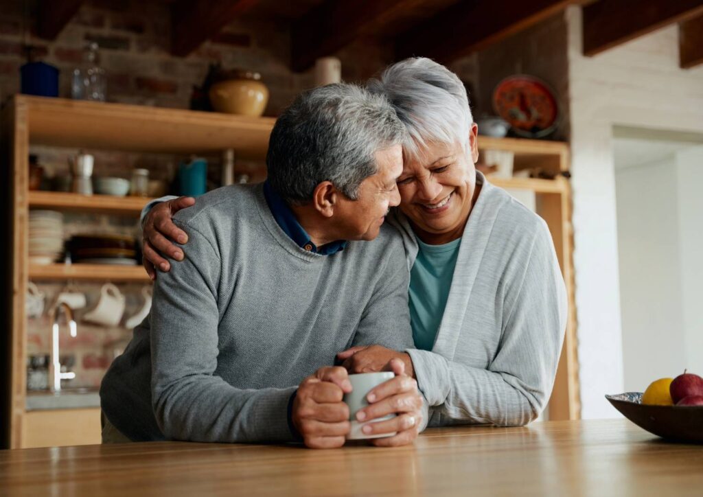 Happy mature couple by kitchen island enjoying the waterline service provided by Goettl.
