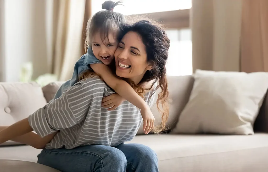 mom and daughter laughing on living room couch after a Goettl ac maintenance service