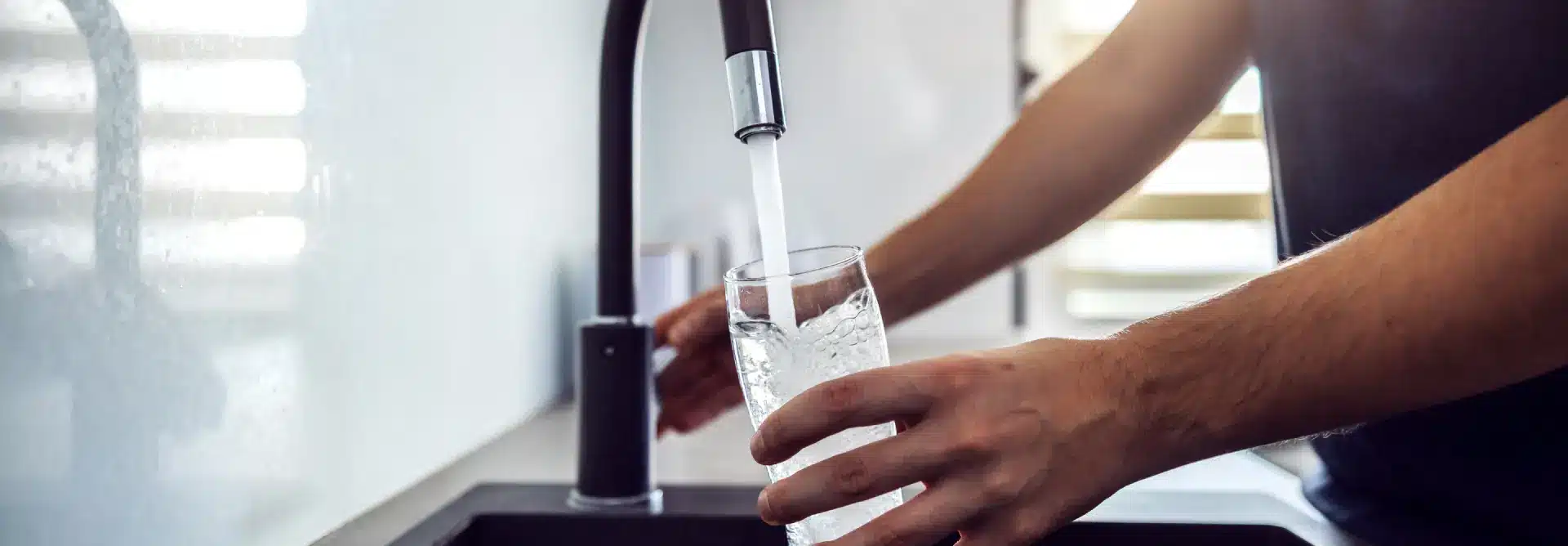 Person filling up their cup with water at their sink