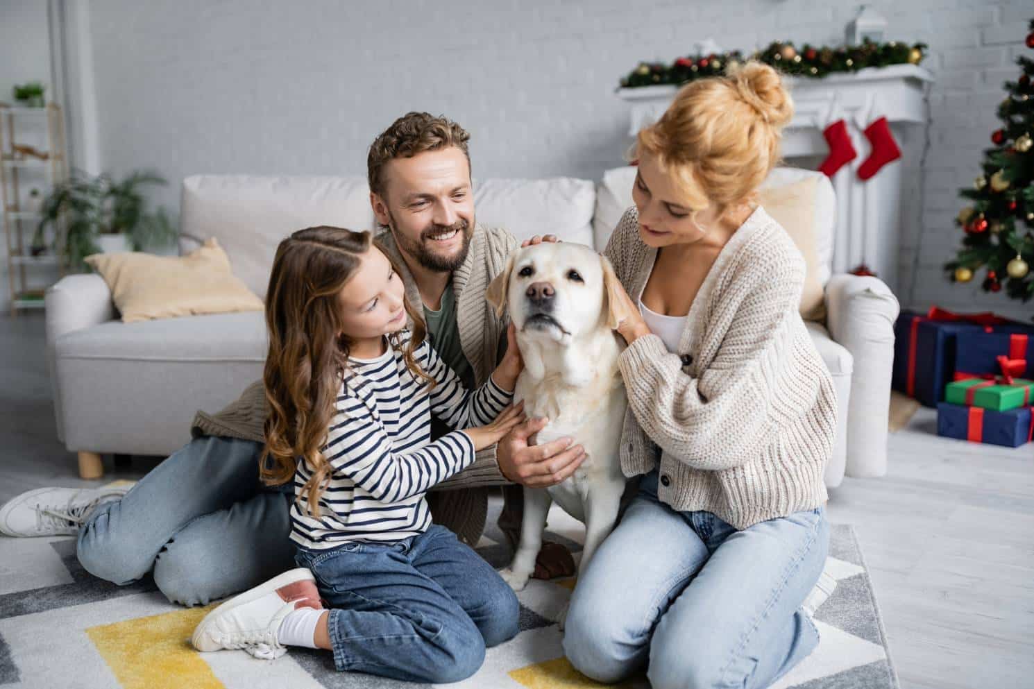 Young happy family with dog on living room floor enjoying newly installed ductless mini-split system.